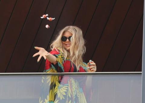 Da varanda do hotel, Fergie joga guloseimas para fãs brasileiros